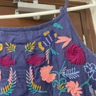 Blue dress with colorful floral embroidery hanging on a rack.