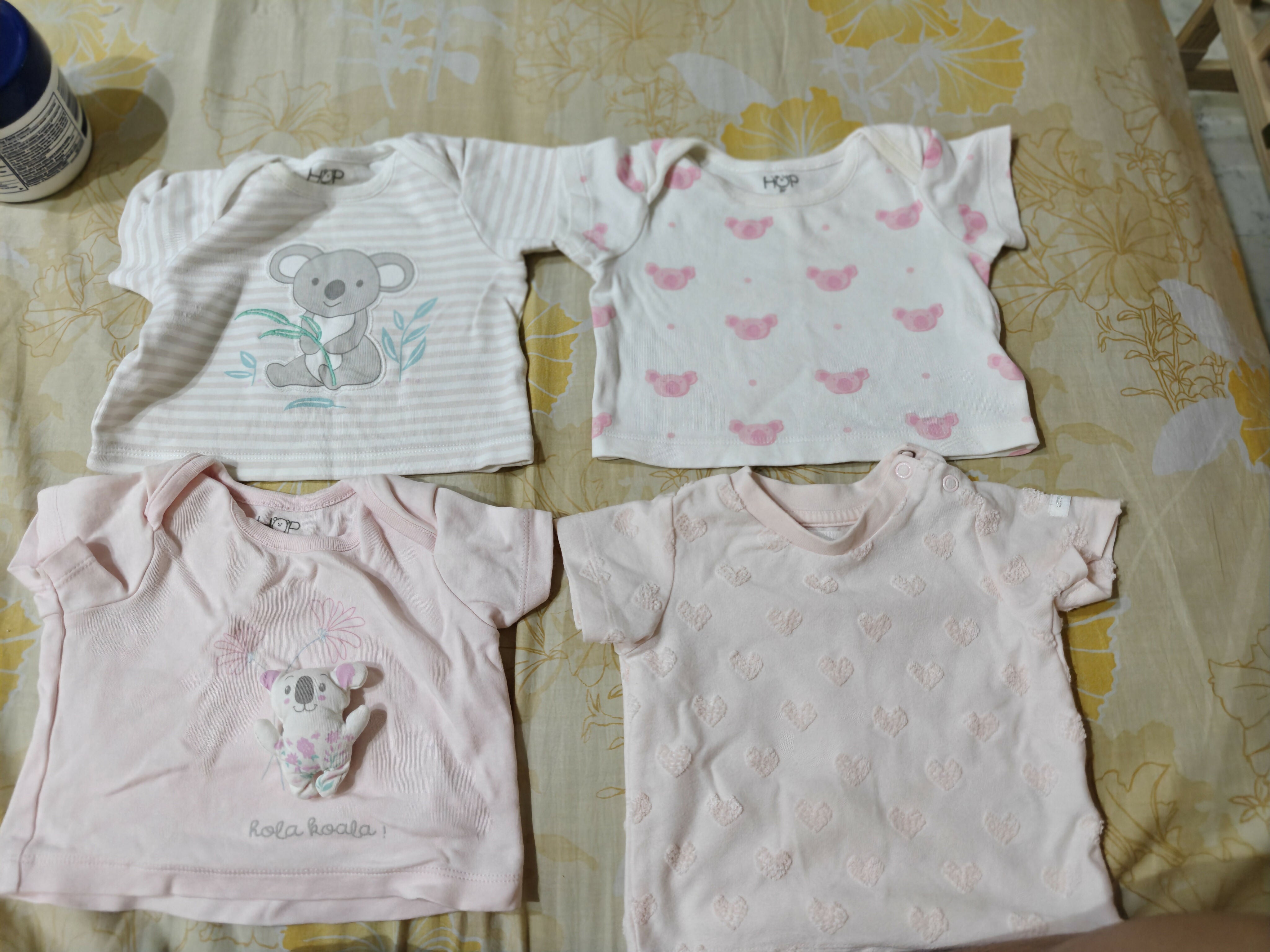 Four baby shirts with different designs on a patterned surface