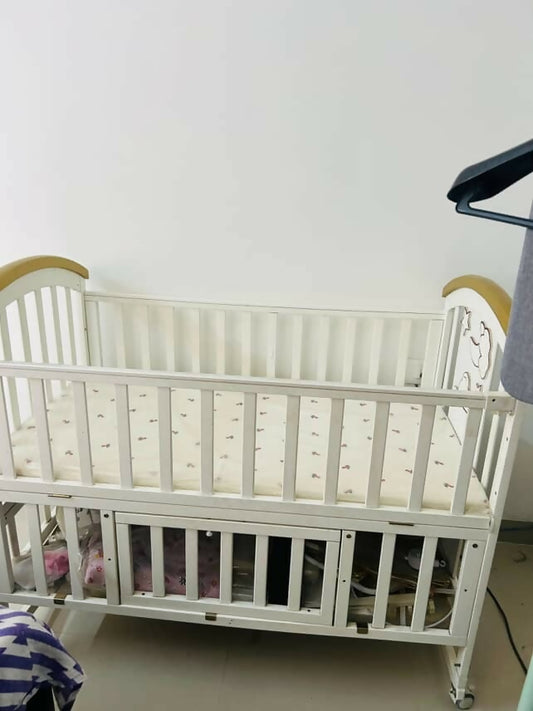 Shop Huny Huny Convertible Baby Cot – Wooden crib with storage, teething rails, wheels, and adjustable height.