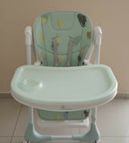 Green and white high chair with butterfly design on a beige background