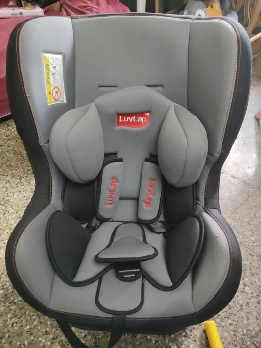 Gray and black car seat with LuvLap branding on a concrete floor.
