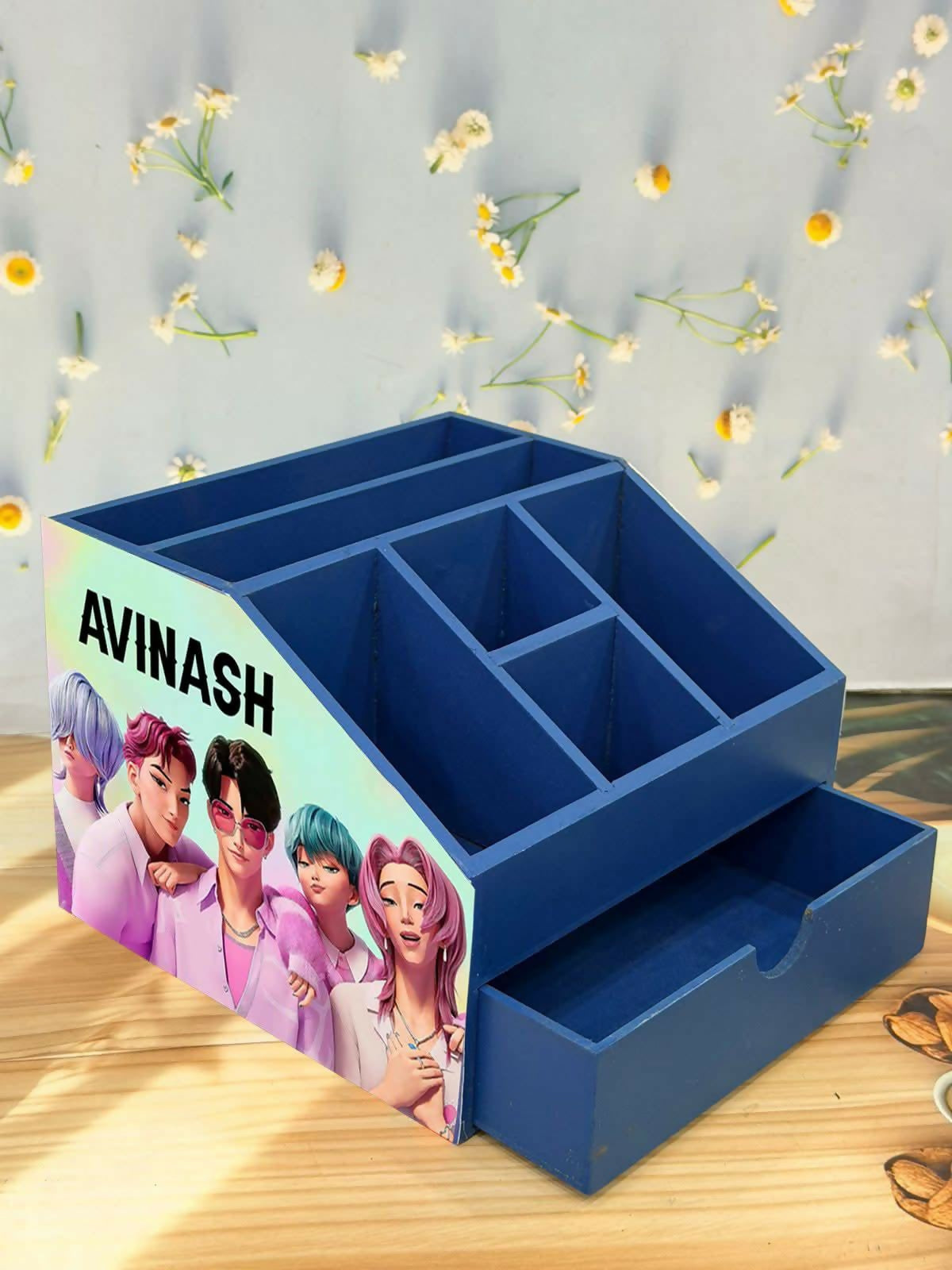 Blue desk organizer with a personalized design on a wooden surface with decorative elements.