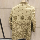 Embroidered traditional outfit on a hanger against a tiled wall.