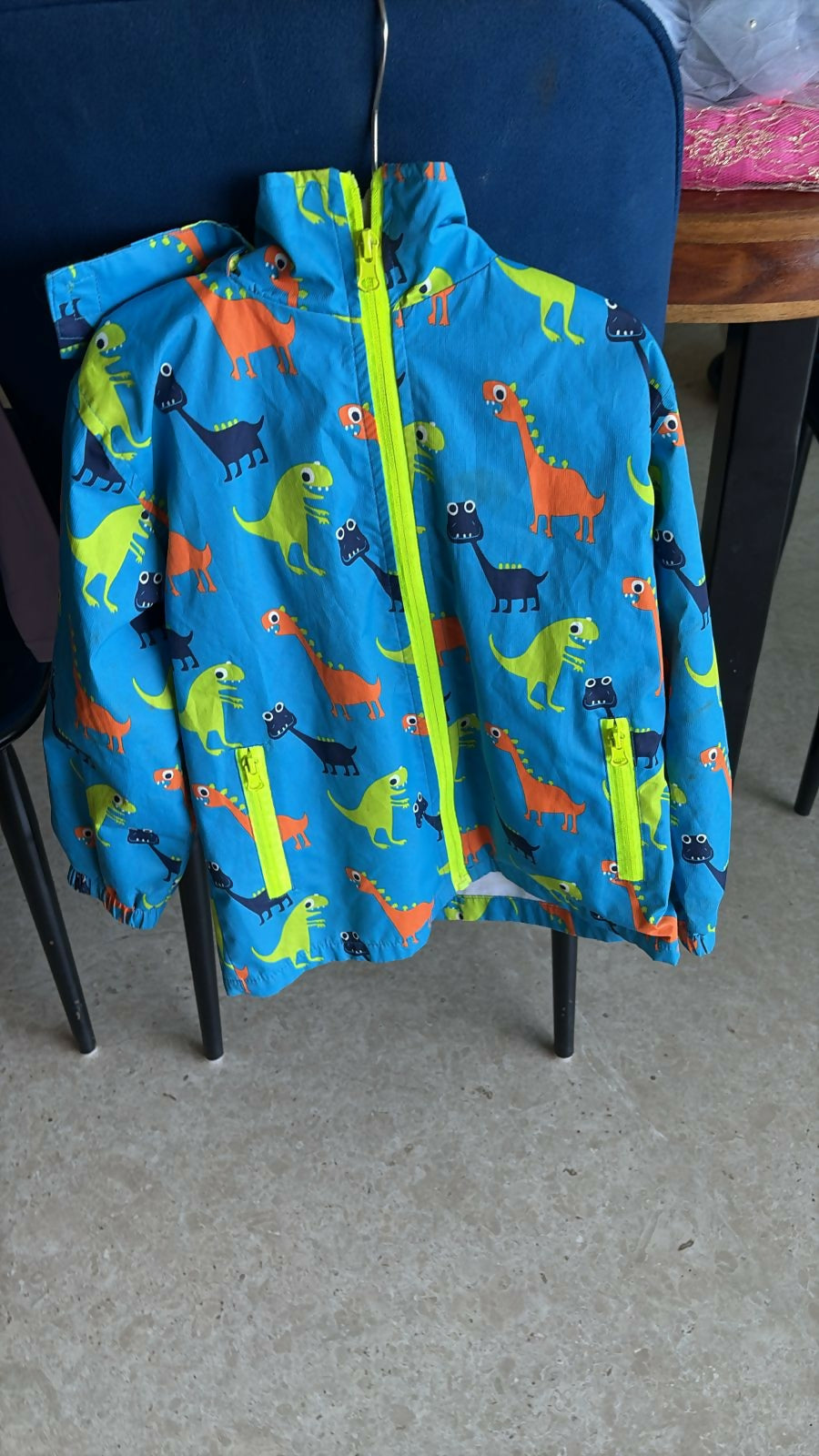 Blue windcheater jacket with multicolored dinosaur print, lightweight fabric, full-zip design, comfortable fit, and stylish protection for outdoor adventures and everyday wear.