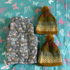 Floral-patterned bag and yellow beanie on a blue fabric background with butterfly designs