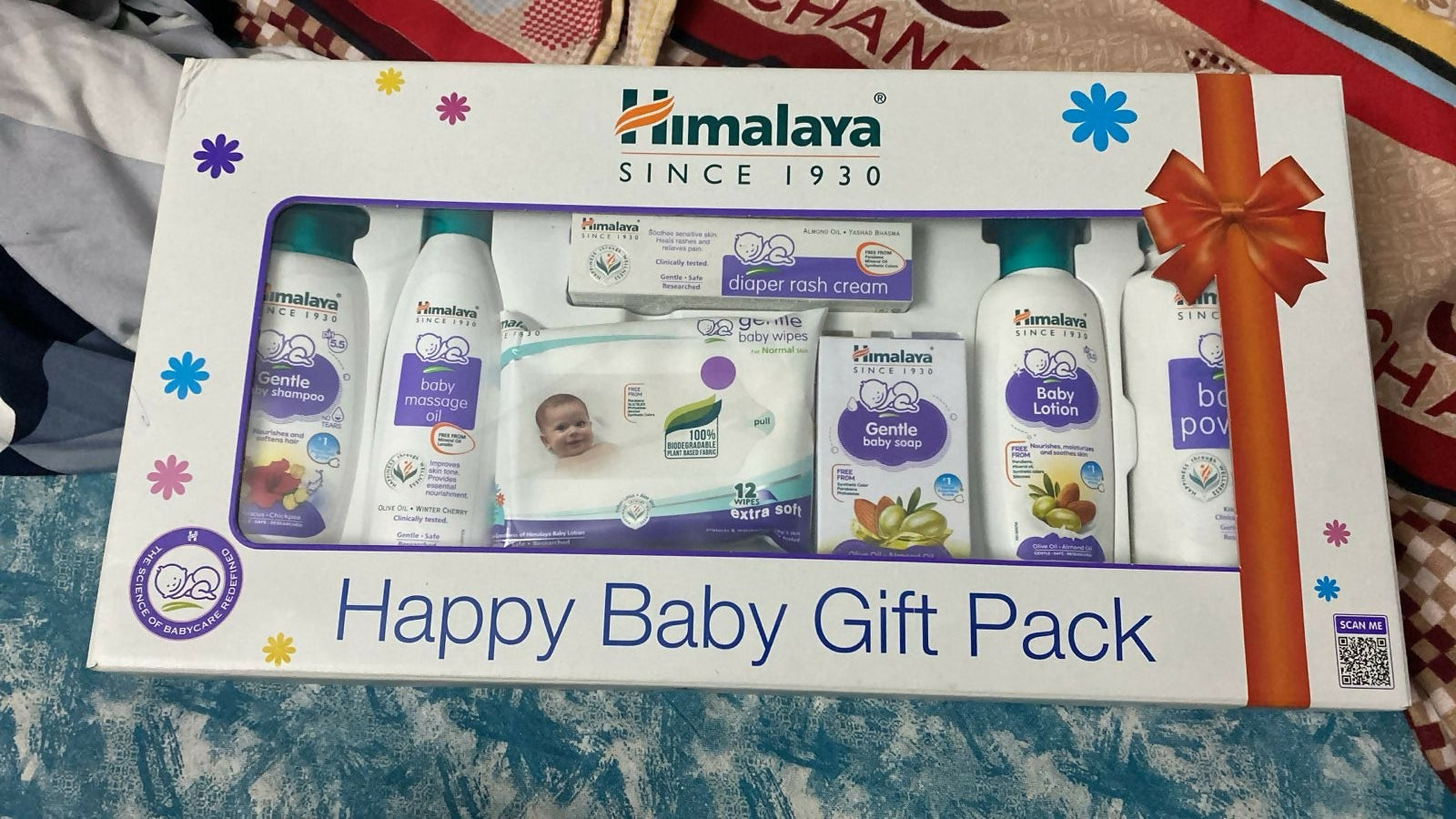 Happy Baby Gift Pack with various baby products on a textured surface