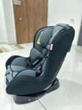 Gray car seat on a white floor with a wooden door in the background