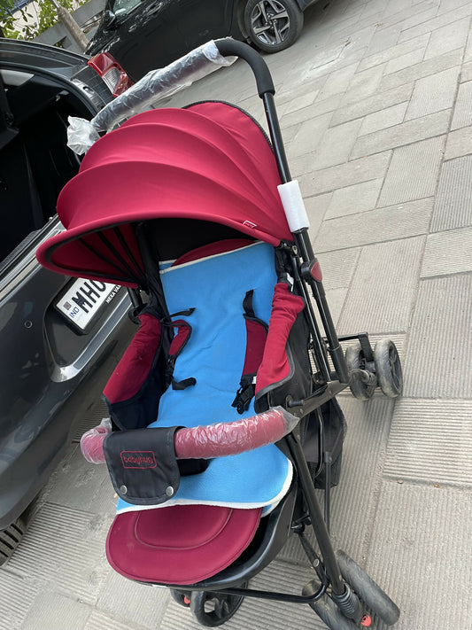 Nearly new red baby stroller with sun canopy, padded seat, lightweight design, and foldable convenience—ideal for on-the-go families!