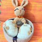 Handmade crochet bunny toy with button details on a wooden surface