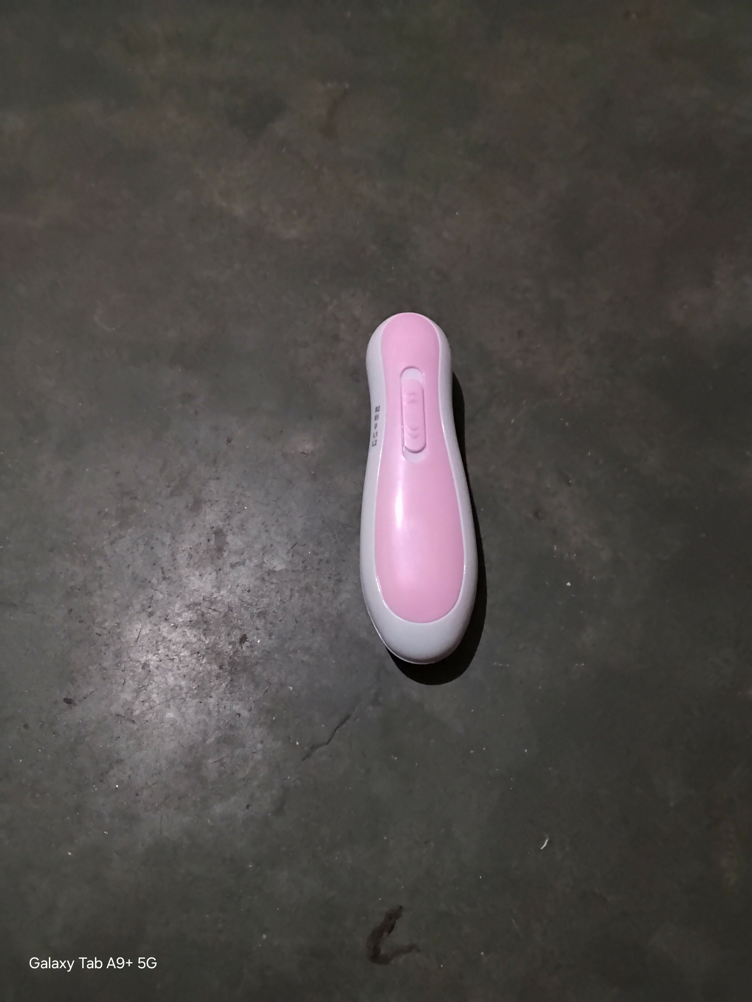 Pink and white electronic device on a dark surface