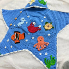 Handmade Crochet Baby Cocoon with Patches featuring a cozy handcrafted design, soft crochet texture, and charming decorative patches, ideal for newborn photoshoots, gifting, and supervised cozy moments.
