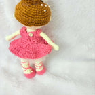 Crocheted doll with a pink dress and brown hat on a white background