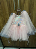 Children's dress with sequin embellishments and tulle skirt on a hanger against a wooden background