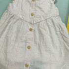 Light-colored dress with button details on a light blue background