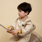Child sitting in a beige high chair against a beige background
