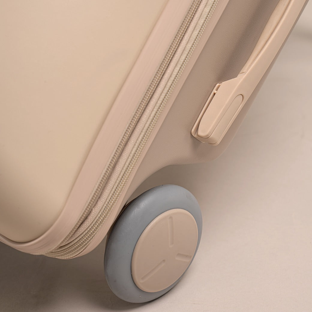 Beige suitcase with a wheel on a light beige background