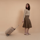 Woman with a beige suitcase against a beige background