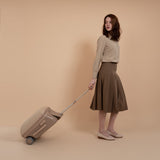 Woman with a beige suitcase against a beige background