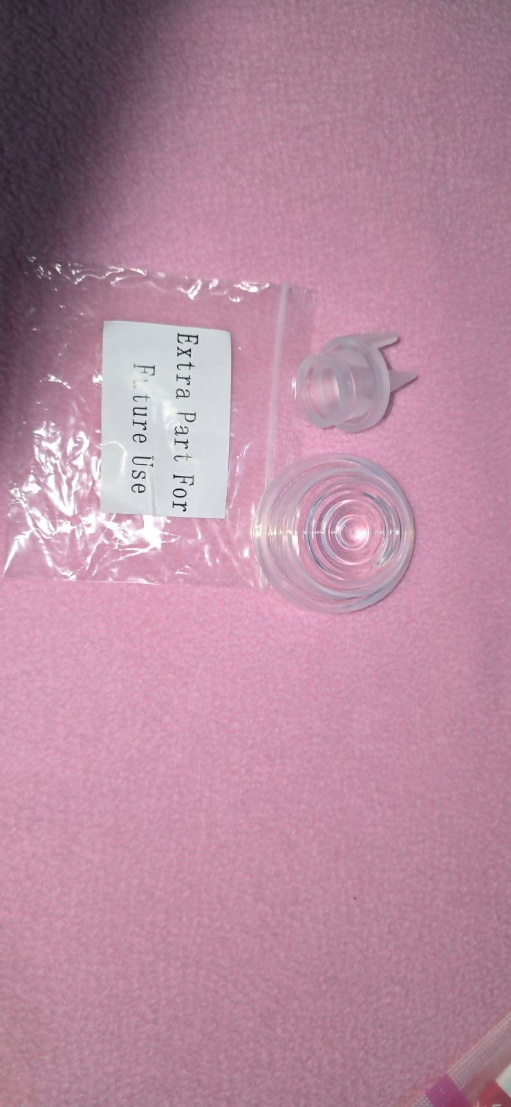 Clear plastic part with packaging labeled 'Extra Part For Pure Use' on a pink background