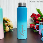 Blue water bottle with 'Kayla' engraving on a wooden surface with flowers in the background
