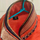 Close-up of a red hat with decorative elements and a blue ribbon on a blurred background