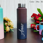 Gradient water bottle with 'Anas' branding on a wooden surface with flowers in the background