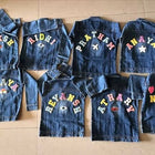 Set of denim vests with colorful letters on a wooden floor