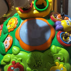 Colorful baby activity table with interactive buttons, music features, shape sorter holes, and small toy elements, designed for early learning and play.