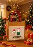 Gift bag with 'Varun' and Christmas-themed design in a festive room with trees and lights.
