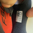 Close-up of a shoe label with a QR code on a black and orange shoe.