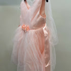 Pink dress with a floral detail on a hanger against a neutral background