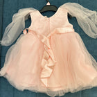 Pink dress with sheer sleeves on a hanger against a blue textured background