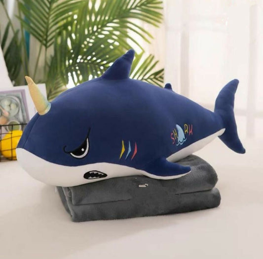 Blue plush shark toy on a blanket 
