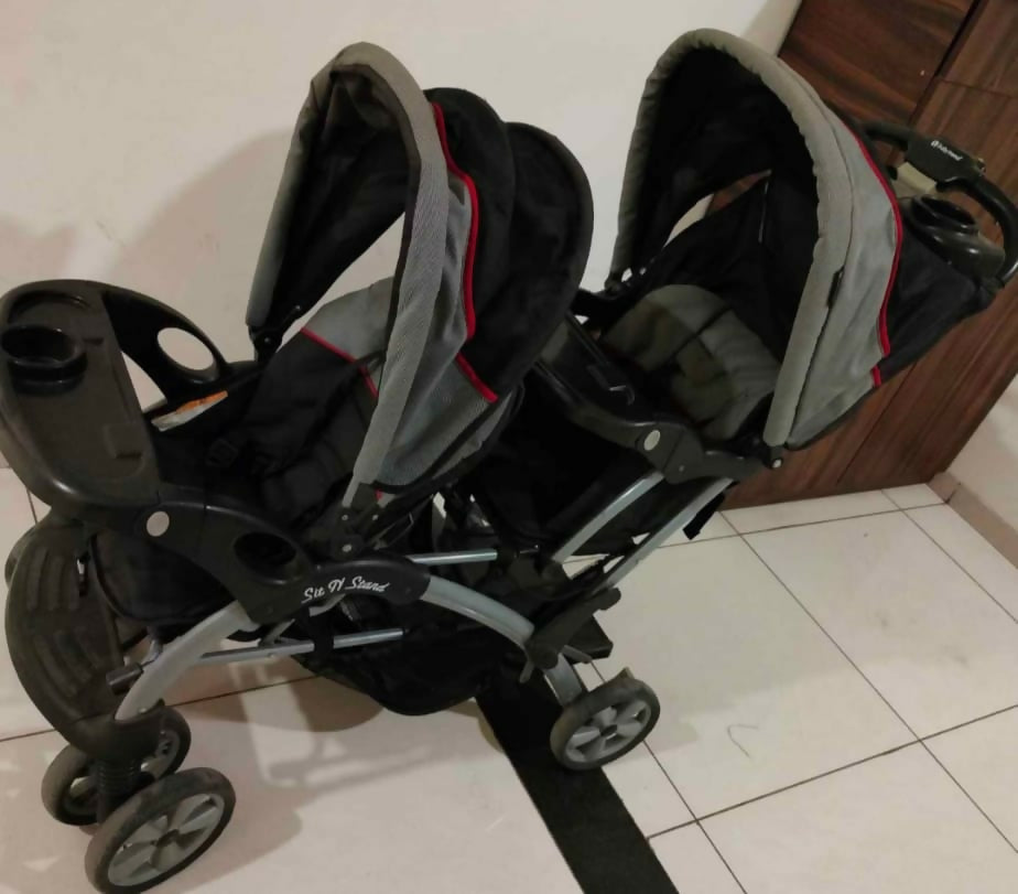 Sit & Stand Twin Baby Stroller with dual seating arrangement, sit-and-stand configuration, comfortable seats, safety harnesses, protective canopy, smooth wheels, and convenient storage for travelling with two children.