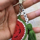 Hand holding a keychain with a watermelon design 