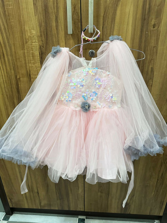 Pink dress with tulle skirt and sequin embellishments on a wooden door background