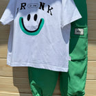 White t-shirt with smiley face design and green pants