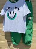 White t-shirt with smiley face design and green pants