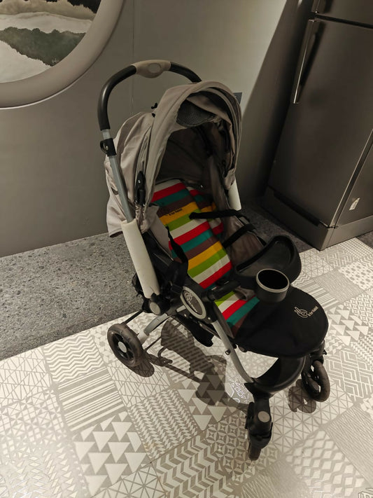 Stroller with a colorful striped blanket on a patterned floor