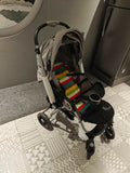 Stroller with a colorful striped blanket on a patterned floor