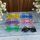 Set of colorful sunglasses with rainbow decorations on a wooden surface.