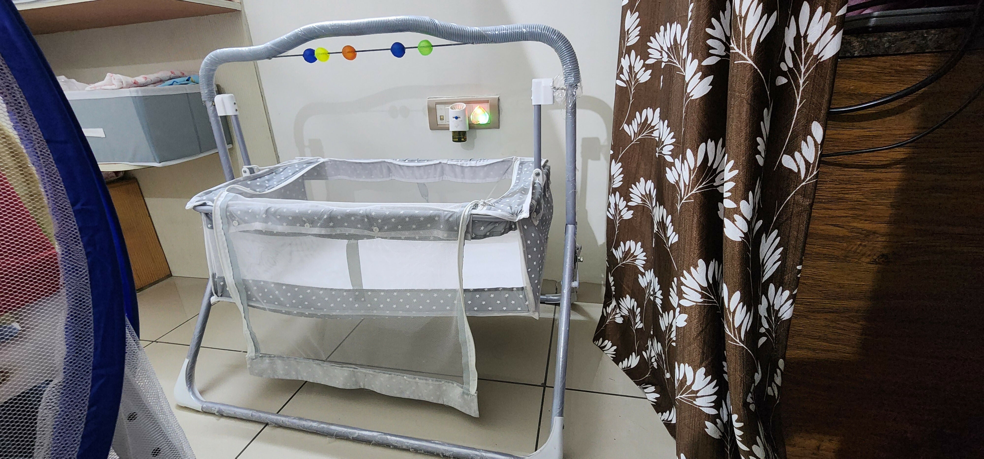 Baby crib with a floral blanket draped over it in a room setting.