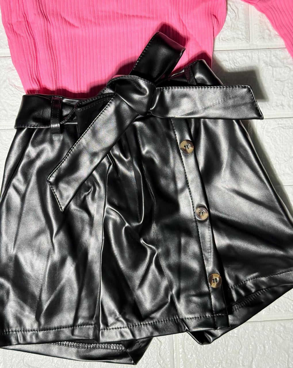 Black leather skirt with buttons and a pink top 