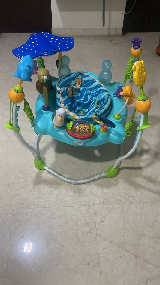 Children's playpen with various toys on a tiled floor