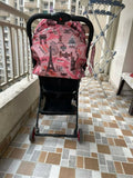 Pink stroller cover with Eiffel Tower design on a tiled balcony floor.