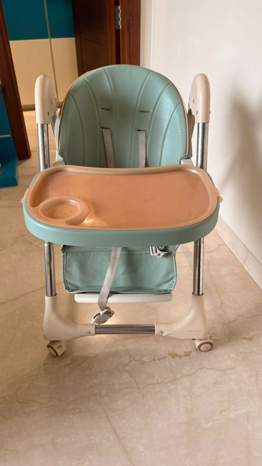 Children's high chair with a tray on a tiled floor.