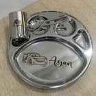 Custom engraved children’s steel dinner set with partition plate, spoon, fork, and tumbler, featuring name ‘Ayan’ with car illustration.