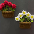 Two crochet flower pots with red flowers and white flowers