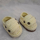 Pair of yellow baby shoes with brown accents on a textured surface.