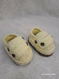 Pair of yellow baby shoes with brown accents on a textured surface.